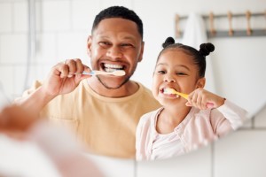 father and daughter brushing teeth